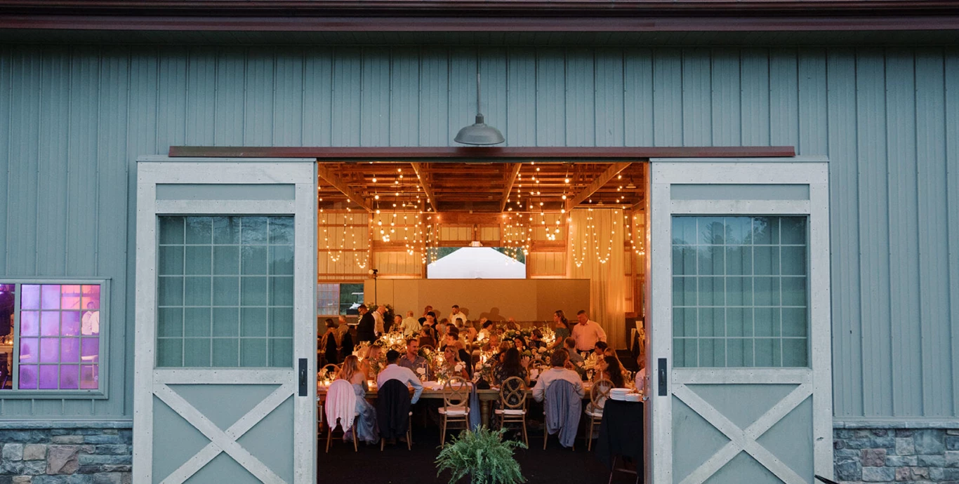 A wedding reception with people seated inside a set of double doors